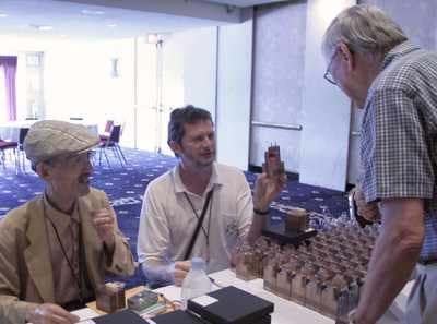 Photo L-R: Nob Yoshigahara & Brian Young (alias Mr Puzzle) sharing puzzles with Jerry Slocum at IPP23 in Chicago August 2003.